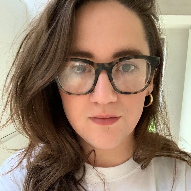 Woman with long dark hair, white tshirt and glasses.