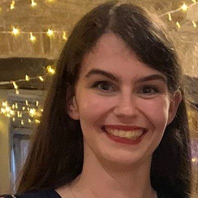 Woman with long dark hair, she is smiling.