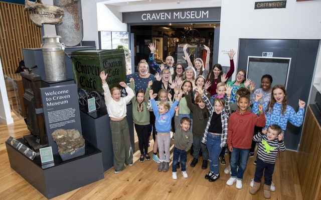 A group of museum staff and children are chearing in the museum foyer